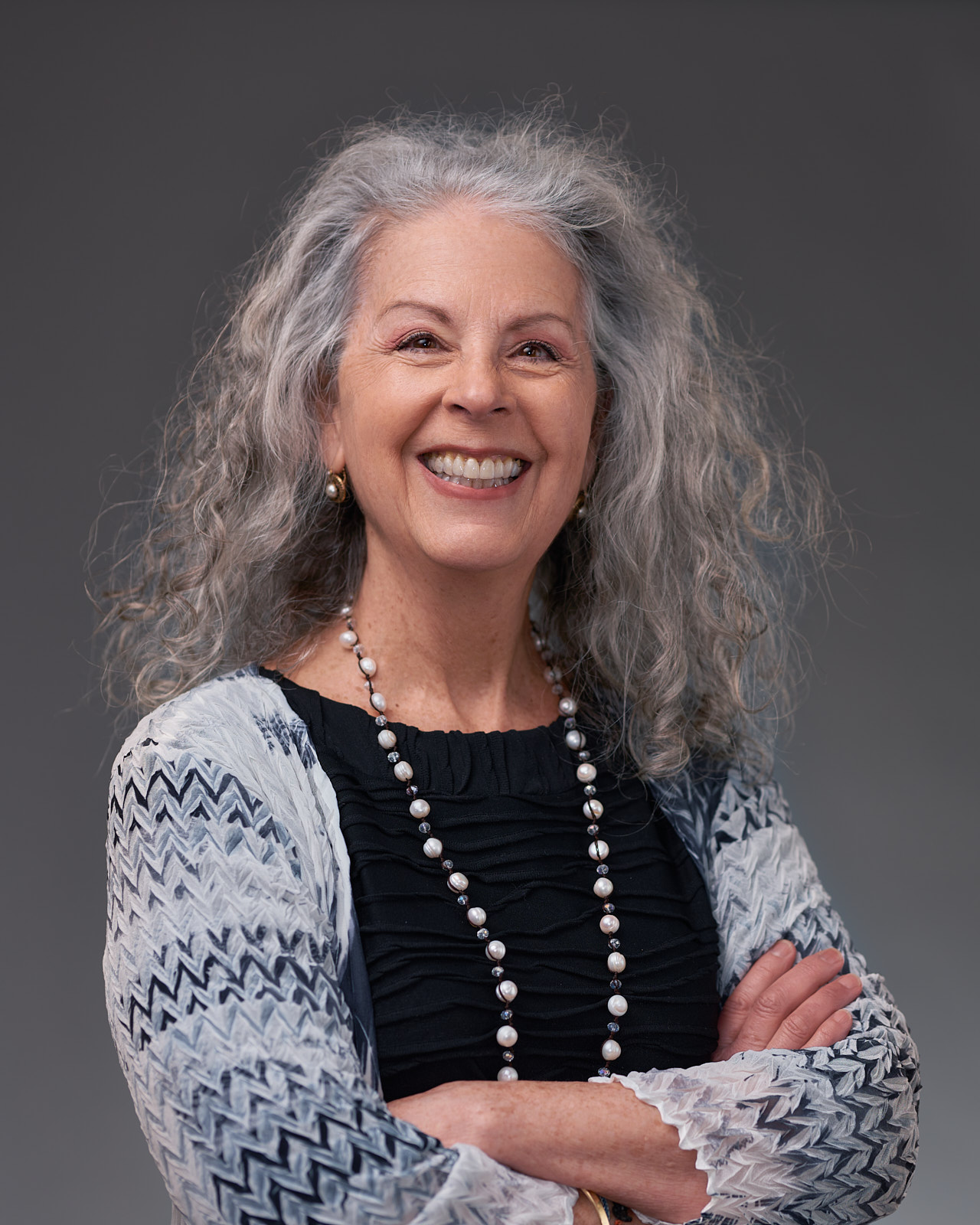 A woman with long grey hair smiling for the camera.