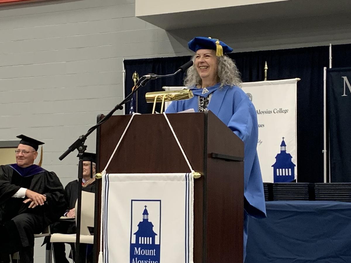 A person in blue graduation gown standing at a podium.